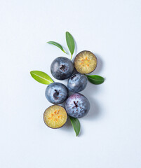 Concept flat lay with a  few juicy blueberries with green leaves on blue background. Top view and copy space