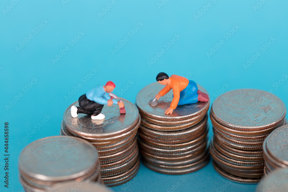 Wall mural Miniature worker dolls repairing coins