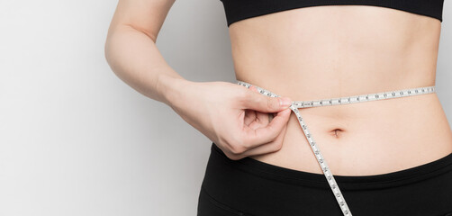 woman measuring her waist with flexible tapeline