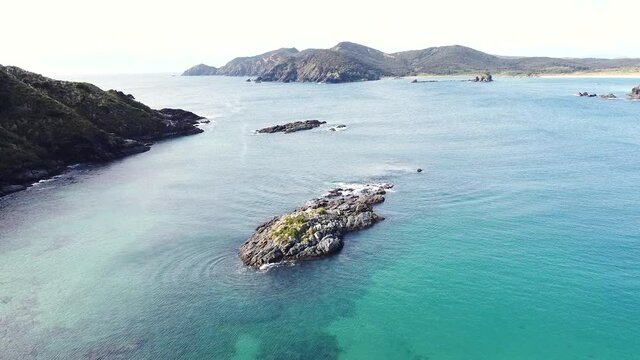 Aerial drone over rocky outcrop in turquoise water in Maitai Bay, Karikari Peninsula, Northland, New Zealand Aotearoa