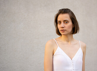 portrait of a young beautiful woman on a gray background, looking at the camera, calm confident serious face