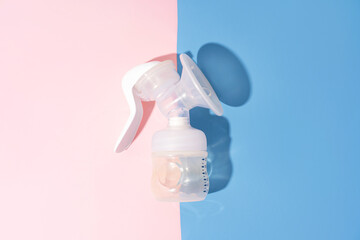 Manual breast pump on blue and pink background with hard shadows