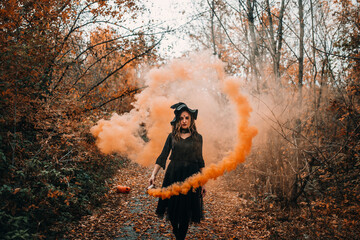 Girl dressed as witch holding smoke bomb in her hands