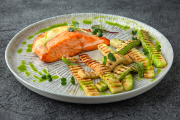 Salmon fillet baked in sauce and grilled zucchini. Ready menu for the restaurant. Neutral gray blue textured background