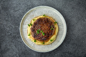 Chopped beef cutlet with walnut and truffle garnished with mashed potatoes. Ready menu for the restaurant. Neutral gray blue textured background
