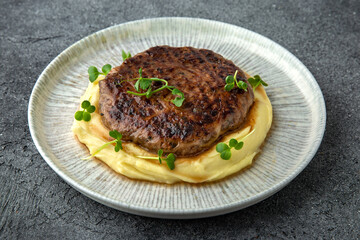 Chopped beef cutlet with walnut and truffle garnished with mashed potatoes. Ready menu for the restaurant. Neutral gray blue textured background