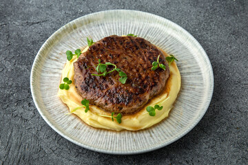 Chopped beef cutlet with walnut and truffle garnished with mashed potatoes. Ready menu for the restaurant. Neutral gray blue textured background