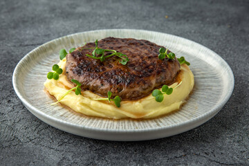 Chopped beef cutlet with walnut and truffle garnished with mashed potatoes. Ready menu for the restaurant. Neutral gray blue textured background