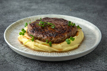 Chopped beef cutlet with walnut and truffle garnished with mashed potatoes. Ready menu for the restaurant. Neutral gray blue textured background