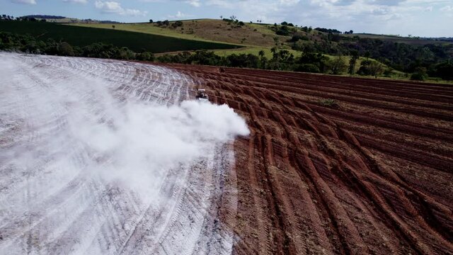 Tractor applying limestone to the soil to correct acidity. 4K.