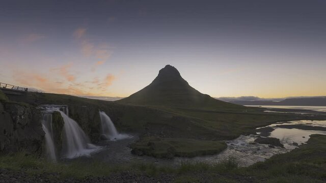 Timelapse of beautiful and powerful of streaming at small waterfall and orange sunlight cover green Kirkjufell mountain in morning,Summer,Iceland.