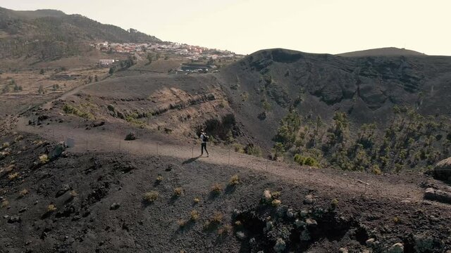 Aerial: One man hiking on a volcano route in La Palma , near the enourmous erosion crater and volcanic landscape, San Antonio, Spain.