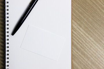 A white notebook with pencil on a wooden table. 