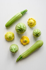 green vegetables zucchini tomatoes and squash on a white table