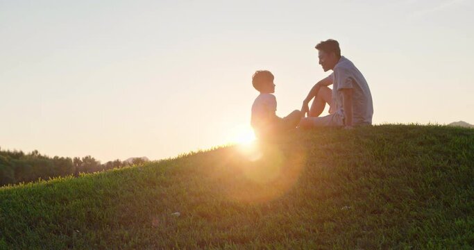 Happy father and son sitting on meadow,4K