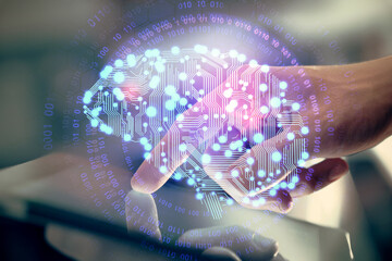 Double exposure of man's hand holding and using a digital device and brain hologram drawing. Data...