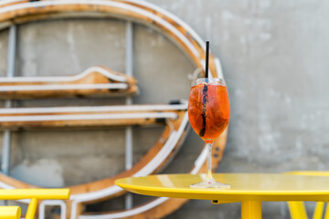 Glass of aperol spritz cocktail on yellow table