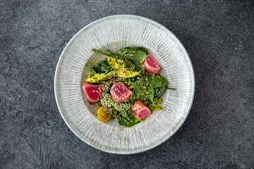 Tuna salad with fresh vegetables. Ready menu for the restaurant. Neutral gray blue textured background