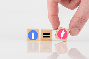 Eine Hand legt Symbole Mann und Frau mit einem Gleichzeichen dazwischen. Konzept Gleichberechtigung.