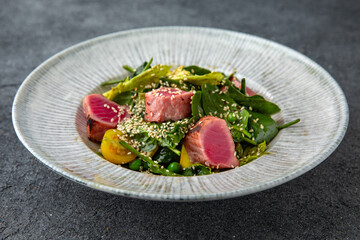 Tuna salad with fresh vegetables. Ready menu for the restaurant. Neutral gray blue textured background
