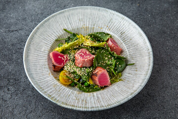 Tuna salad with fresh vegetables. Ready menu for the restaurant. Neutral gray blue textured background