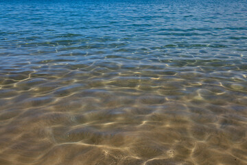 Summer sea background. Texture of water surface. Shining blue water ripple pattern.