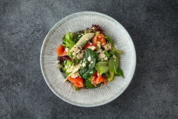 Hearty dietary salad made from salmon, avocado, herbs and sauce. Ready menu for the restaurant. Neutral gray blue textured background