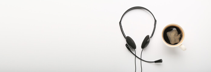 Headset and cup of coffee on white background with space for text