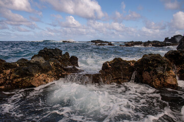 Fototapeta na wymiar Sea collides with the stones and sand of a beach. Sea waves lash line impact rock.