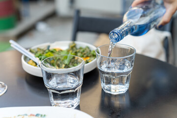 Woman's hands pouring water into glass, close-up