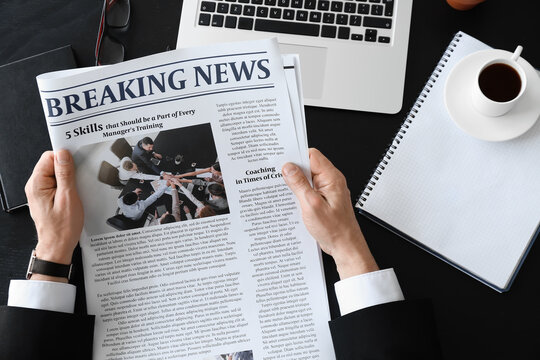 Mature businessman reading newspaper in office