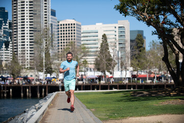 Athletic young man running in the city nature.