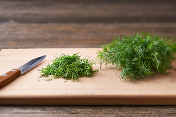 Fresh chopped green dill leaves on a cutting board, selective focus.