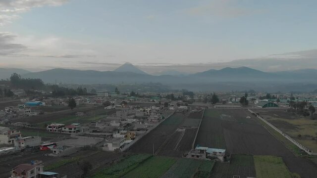 Town and volcano during sunrise in Andes of Ecuacor. Volcano Tungurahuaand Andean Peaks. High Altitude Drone Shot Of Ambato, Ecuador