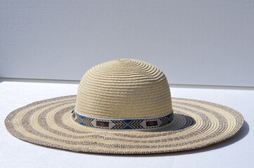 Fototapeta na wymiar Straw female new hat with brown stripes on a white background. Summer vacation concept.