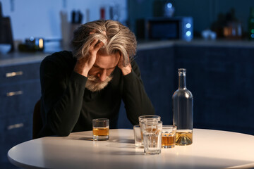 Drunk senior man in kitchen at night