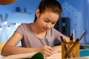 Little girl doing homework at home late in evening