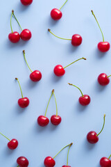 Ripe red sweet cherries on blue background. Flat lay, top view.