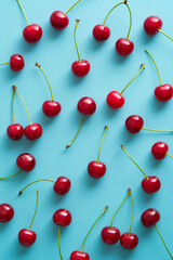 Obraz na płótnie Canvas Flat lay red ripe cherry berries on turquoise background. Top view