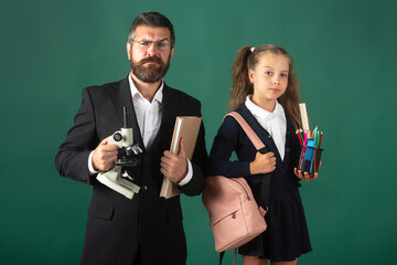Portrait of serious teacher and pupil school girl ready to school. Portrait of dad and little girls...