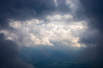Fototapeta na wymiar storm clouds through the rays of the sun from the plane window, horizontal.