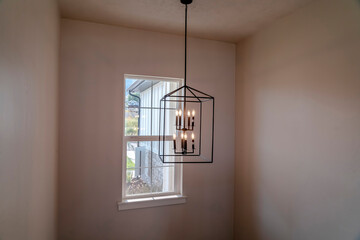 Chandelier with modern geometric design against small window inside a home