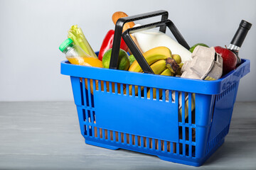 Fototapeta premium Shopping basket with food on table near light wall