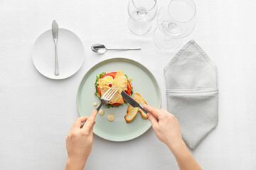 Woman eating tasty Caesar salad on light background, closeup