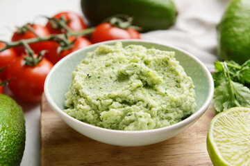 Bowl with tasty guacamole and lime on table, closeup