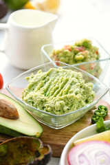 Bowl with tasty guacamole on table, closeup