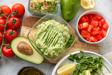 Bowl with tasty guacamole and vegetables on table