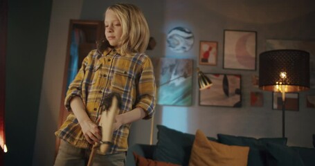 Happy blonde boy riding wooden toy horse, child with long fair hair jumping at home after kindergarten or school, kid playing cowboy, holding rat on his shoulder, fun during coronavirus quarantine. 