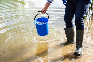 Bucket with water. A man draws water from a pond.