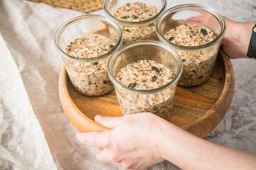 Brotteig von Vollkorn Brot mit Kürbiskernen, Haferflocken, Sonnenblumenkernen, Chia und Leinsaat roh im Glas für Einkochen und Vorrat auf Leinentuch, Holzbrett und Marmor Hintergrund hell